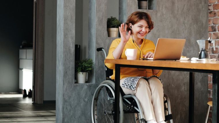 Photo of a lady in a wheel chair having a meeting over video conferencing using a laptop