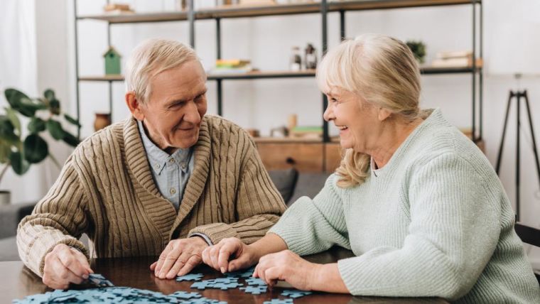 Two elderly people having fun doing a jigsaw together